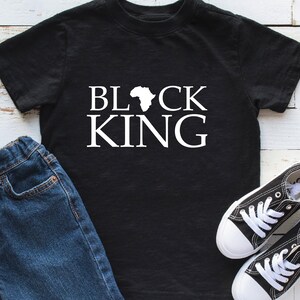 Puede incluir: Camiseta negra con el texto "BLACK KING" en letras blancas y un contorno del continente africano entre las palabras.
