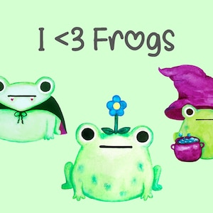 Op de afbeelding: Waterverfillustratie met drie groene kikkers. Eén kikker is verkleed als vampier, een andere heeft een bloem op zijn hoofd en de derde is een heks met een paarse hoed. De tekst "I <3 Frogs" staat bovenaan.