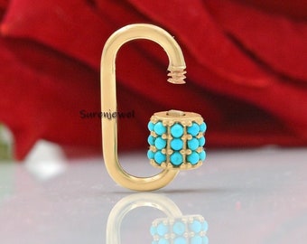 May include: Gold charm with a turquoise stone design. The charm is shaped like a hook and has a small cylinder with turquoise stones on it.