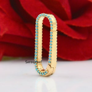 May include: Gold oval-shaped connector with a turquoise stone border. The connector is designed to be used for jewelry making.