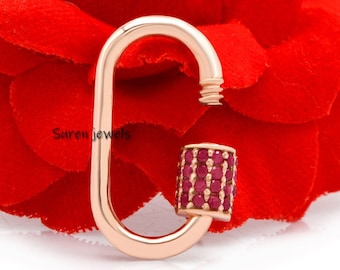 May include: Rose gold oval shaped charm with a red ruby stone accent. The charm is on a red rose.