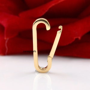 May include: Gold-toned metal clasp with a spring-loaded mechanism. The clasp is designed to be used for attaching jewelry or other items.