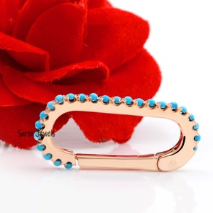 May include: A rose gold oval-shaped clasp with a turquoise stone border. The clasp is a jewelry finding for necklaces, bracelets, or other jewelry pieces.