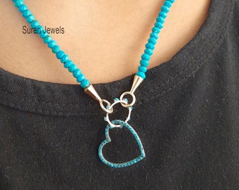 May include: A turquoise gemstone necklace with a silver heart pendant. The necklace is made of small, faceted beads and the heart pendant is set with smaller turquoise stones.