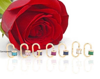 May include: A set of eight gold hoop earrings with a variety of coloured gemstones. The earrings are arranged in a row on a white background. The gemstones are turquoise, pink, purple, red, blue, clear, and green.