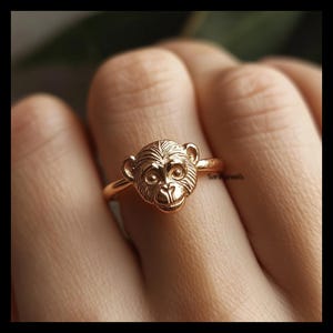 Könnte beinhalten: Ein goldener Ring mit einem Affenkopf-Design. Das Gesicht des Affen ist detailliert und hat einen realistischen Ausdruck.