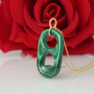 May include: A pendant shaped like a soda can tab carved from green malachite with distinct dark and light green banding. The pendant is suspended from a thin gold-colored chain and features a small gold-colored bail at the top.