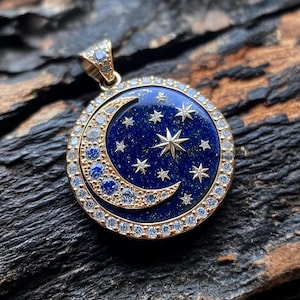 Op de afbeelding: Een gouden ketting met een hanger van blauwe lapis lazuli, gezet in de vorm van een halve maan. De maan is omringd door een halo van kleine witte diamanten en heeft een grote ster in het midden.