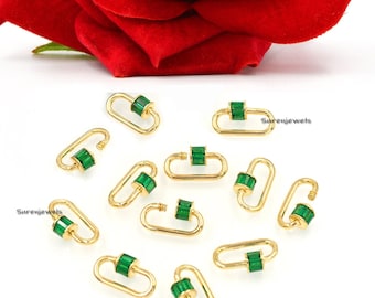 May include: A group of 12 gold-toned lobster clasps with green gemstone accents. The clasps are scattered on a white surface.