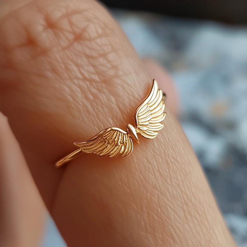May include: A gold-toned ring with a delicate design of two angel wings.