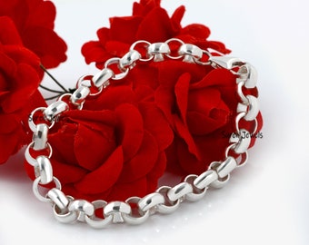 May include: A silver chain bracelet with a thick, rounded link design. The bracelet is displayed on a bed of red roses.