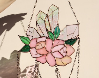 May include: A stained glass window hanging with a pink flower and crystal design. The hanging features a copper chain with green glass beads.