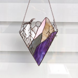 May include: A stained glass window hanging with a copper chain. The window depicts a purple, pink, and brown mountain scene with a bird flying overhead.
