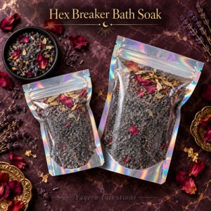 May include: Two holographic pouches filled with Hex Breaker Bath Soak, containing dark salt, dried lavender, and red rose petals. The text Hex Breaker Bath Soak and Yaqeen Intentions is visible. A small black bowl contains the same mixture.