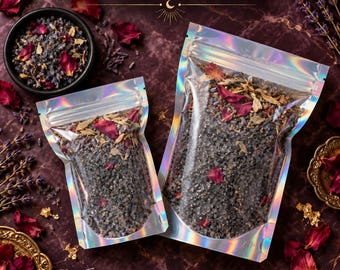 May include: Two holographic pouches filled with Hex Breaker Bath Soak, containing dark salt, dried lavender, and red rose petals. The text Hex Breaker Bath Soak and Yaqeen Intentions is visible. A small black bowl contains the same mixture.