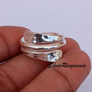 Può includere: Un anello avvolgente in argento martellato con una finitura testurizzata. L'anello è in argento sterling ed è regolabile per adattarsi alla maggior parte delle dimensioni delle dita.