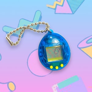 May include: A blue handheld digital pet toy with a silver chain. The toy has a small screen displaying a digital character and three yellow buttons below. The background features a colorful, geometric design.