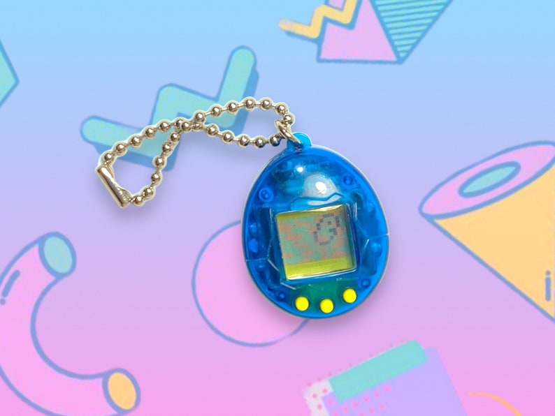 May include: A blue handheld digital pet toy with a silver chain. The toy has a small screen displaying a digital character and three yellow buttons below. The background features a colorful, geometric design.