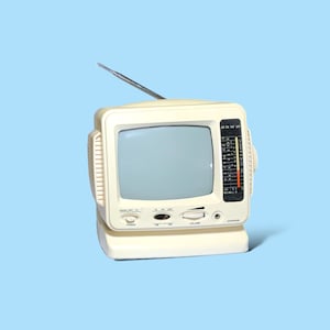 May include: A vintage cream-colored portable television set with a silver antenna. The TV has a small screen, a tuning dial, and a speaker. The design is retro, with a built-in stand and a radio dial. The background is a light blue.