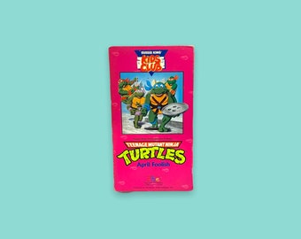 May include: A pink Burger King Kids Club VHS tape featuring the Teenage Mutant Ninja Turtles. The tape has a colorful illustration of the turtles and the text "April Foolish".