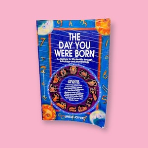 May include: A book titled "The Day You Were Born" with a blue cover and a circular zodiac design. The book's cover features the text "The Day You Were Born" and "A Journey to Wholeness through Astrology and Numerology."