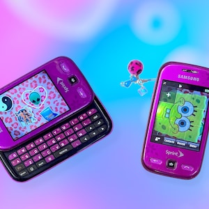 May include: Two purple Samsung Sprint cell phones with different screens. One phone is open, displaying stickers on a leopard print background. The other phone shows a SpongeBob SquarePants image. A charm hangs between the phones.