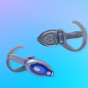 May include: Two gray and blue wireless headphones with ear hooks. The headphones have a rounded design with blue accents and buttons. The ear hooks are a translucent gray color. The background is a gradient of blue and purple.