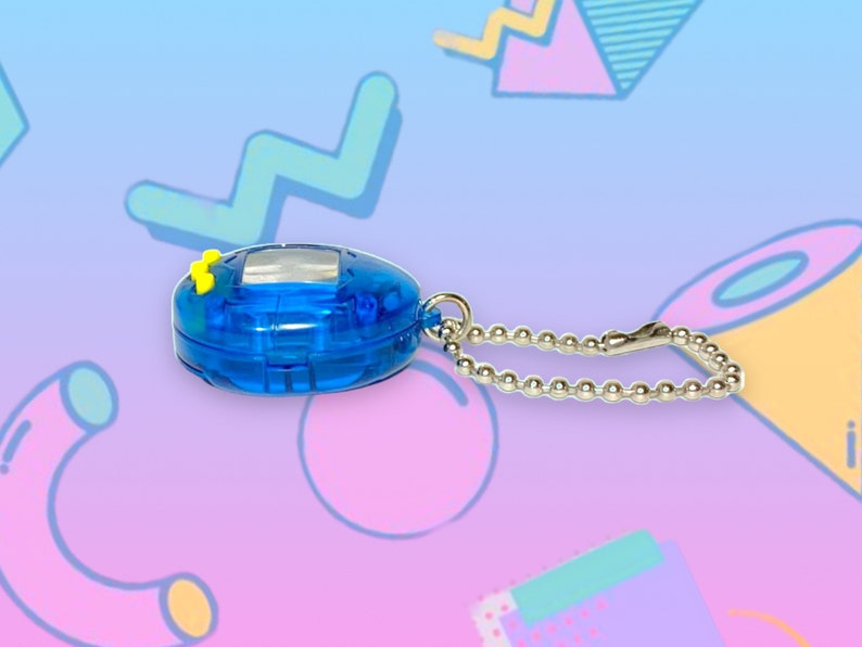 May include: A blue handheld digital pet toy with a silver chain. The toy has a small screen and yellow buttons. The background is a colorful, abstract design with geometric shapes in shades of blue, pink, and purple.