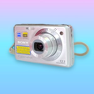 May include: Silver Sony Cyber-shot digital camera with a Carl Zeiss lens. Features include 12.1 megapixels, optical zoom 4x, and full HD 1080 image quality. Includes a wrist strap and is ideal for capturing photos and videos.