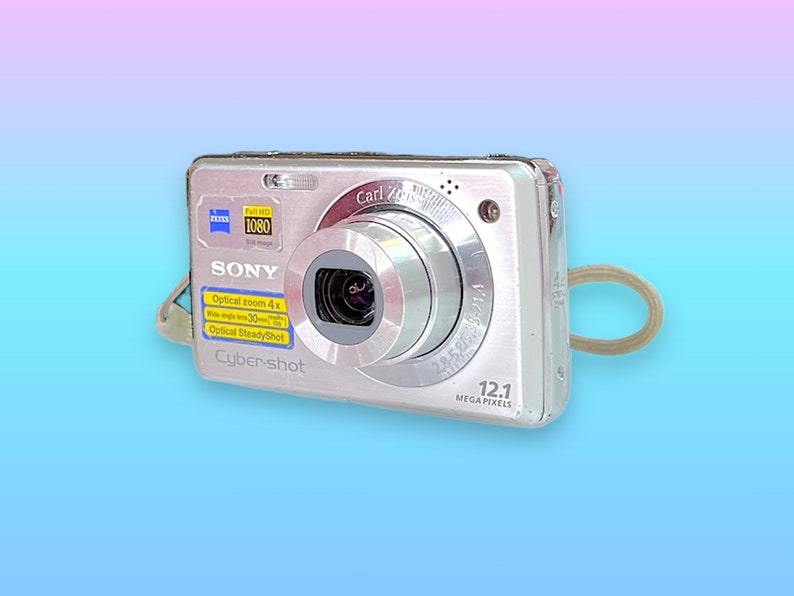 May include: Silver Sony Cyber-shot digital camera with a Carl Zeiss lens. Features include 12.1 megapixels, optical zoom 4x, and full HD 1080 image quality. Includes a wrist strap and is ideal for capturing photos and videos.