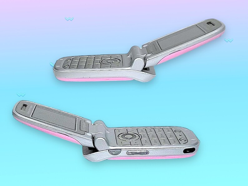 May include: Two silver flip phones with pink accents are displayed against a gradient blue and pink background. The phones are open, revealing the keypad and screen. The design is a retro style.