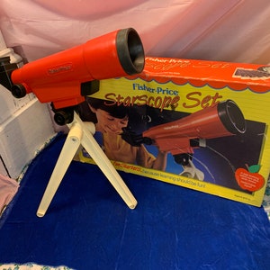 May include: A red Fisher-Price Starscope Set toy telescope with a white tripod, and a box with the same telescope image. The box reads "Starscope Set" and "Fun Starters because learning should be fun!"