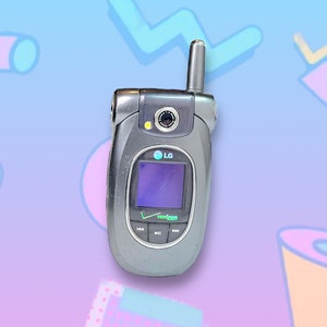 Puede incluir: Un teléfono plegable LG plateado con el logotipo de Verizon. El teléfono tiene una pantalla pequeña, una cámara y una antena retráctil. El fondo es un diseño colorido de temática retro.