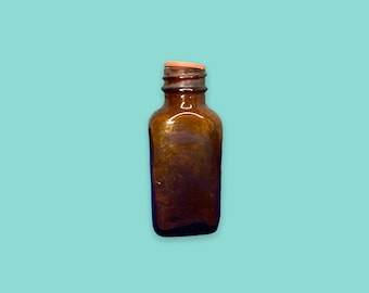 以下が含まれることがあります： 正方形の底と細い首を持つ、小さな茶色のガラス瓶。 ボトルには明るい茶色のキャップが付いています。 背景は無地の明るいティール色です。 このボトルは、液体を保管するためのものです。