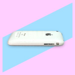 May include: A white iPhone with the Apple logo on the back. The phone has a silver trim and a speaker and charging port on the bottom. The phone is set against a pink and blue background.