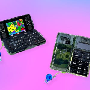 May include: Two LG flip phones with camouflage-patterned cases and blue beaded charms. One phone is open, displaying a colorful cartoon frog image on the screen and a full keyboard. The other phone is closed.