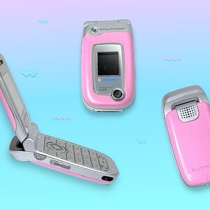 May include: Three pink Sony Ericsson flip phones are displayed against a gradient blue and purple background. One phone is open, revealing the keypad and screen. The other two phones are closed, showcasing the pink exterior and silver accents. The phones are angled to show different views.