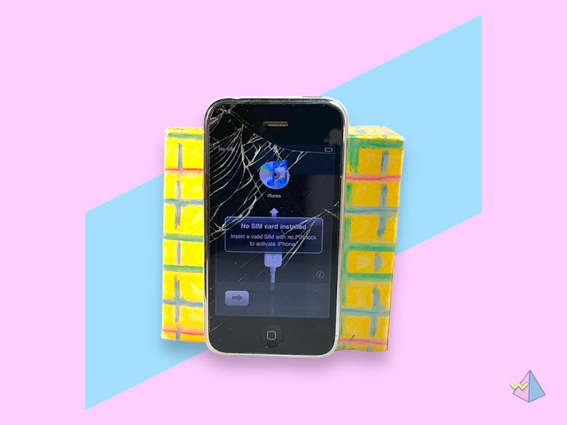May include: A cracked black iPhone with a white border displays an iTunes icon and a message to insert a SIM card. Two yellow and green rectangular blocks flank the phone against a pink and blue background.