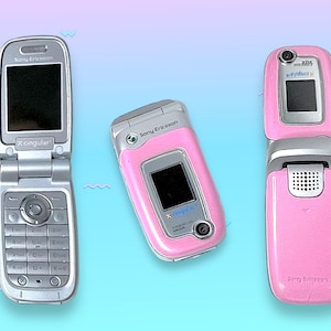 May include: Three open flip phones in a row. The phone on the left is silver with a black screen and the Cingular logo. The middle phone is pink with a black screen. The phone on the right is pink with a black screen and a camera.