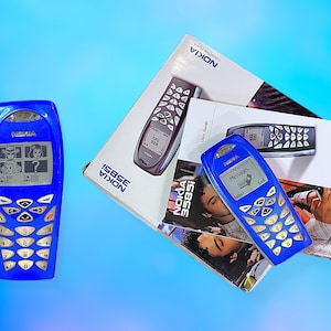Peut inclure: Plusieurs téléphones portables Nokia 3585i bleus vintage, avec leurs emballages et guides d'utilisation d'origine. Les téléphones ont un clavier et de petits écrans affichant des graphiques et du texte. L'emballage porte le logo Nokia.