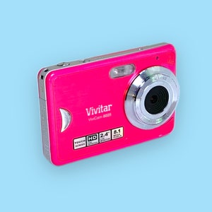 May include: A vibrant pink Vivitar Vivicam 8025 digital camera. The camera features a silver lens and flash, with the text "Vivitar Vivicam 8025" and "Touch Screen". It has a 2.4" LCD screen and 8.1 megapixels.