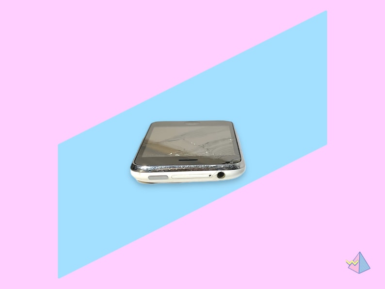 May include: A damaged smartphone with a cracked screen. The phone has a black screen and a white frame with a silver trim. The background is a diagonal split of light blue and pink.