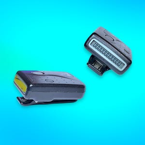 May include: Two black pagers with a digital display and a belt clip. One pager has a visible display with a series of rectangles. The other pager has a yellow light on the side. The background is a gradient of blue.