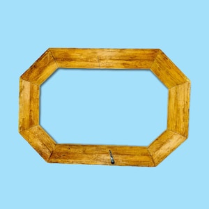 May include: A light brown, octagonal wooden picture frame. The frame has a natural wood grain and a simple, rustic design. The frame is empty, with a light blue background.