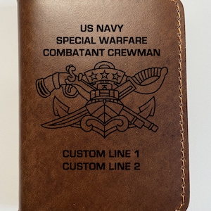May include: Brown leather wallet with the text "US Navy Special Warfare Combatant Crewman" and a Navy Seal insignia. The wallet also has the text "Custom Line 1 Custom Line 2".
