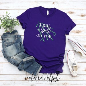 May include: Purple t-shirt with a white graphic that says "I put a spell on you" with green lightning bolts.