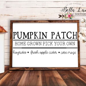 May include: A wooden framed sign with the words "PUMPKIN PATCH" in large black letters. Below, it reads "HOME GROWN PICK YOUR OWN" and lists "hayrides, fresh apple cider, corn maze." The sign is on a wooden surface.
