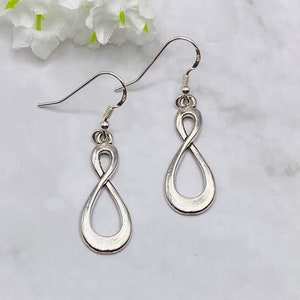 May include: A pair of silver infinity symbol earrings with a dangling design. The earrings have a simple, elegant style.