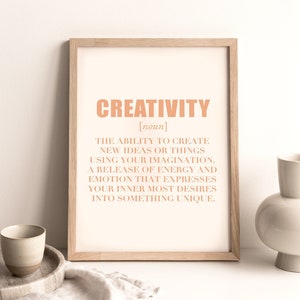 May include: A framed print with a peach-coloured background and the word "CREATIVITY" in a bold, peach-coloured font. The definition of creativity is written in a smaller, peach-coloured font below the word.