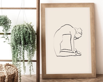 Op de afbeelding: Een zwart-witte lijntekening van een persoon in een yogapose, afgedrukt op crèmekleurig papier en ingelijst in een lichtbruin houten lijst.